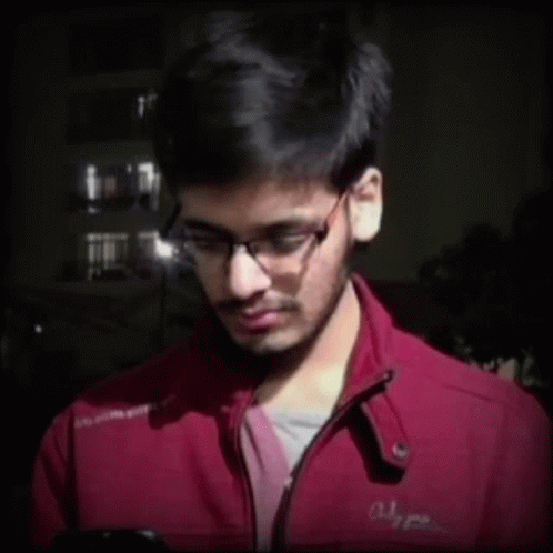 A Young Man Wearing Glasses And A Red Jacket With The Word Alpha On The Front GIF