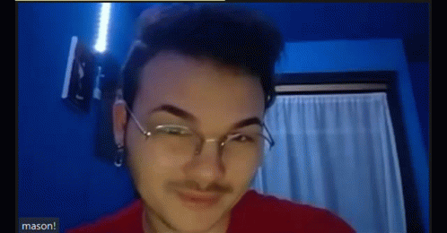 A Young Man Wearing Glasses And A Red Shirt Is Making A Funny Face . GIF