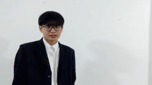 A Young Man Wearing Glasses And A Suit Is Making A Funny Face GIF