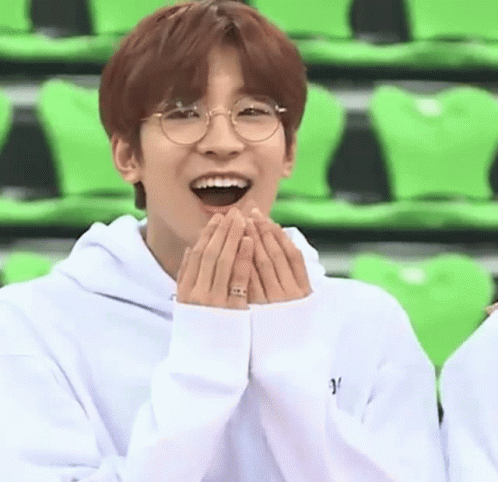 A Young Man Wearing Glasses And A White Hoodie Is Laughing With His Hands On His Face . GIF
