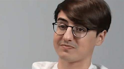 A Young Man Wearing Glasses And A White Shirt Is Making A Silly Face . GIF