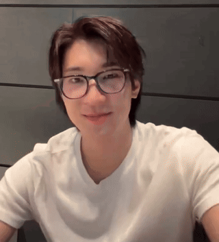 A Young Man Wearing Glasses And A White Shirt Looks At The Camera . GIF