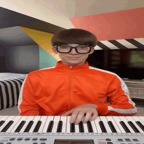 A Young Man Wearing Glasses Is Playing A Keyboard GIF