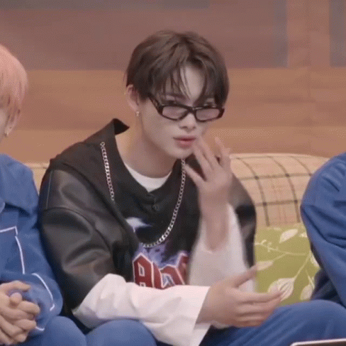 A Young Man Wearing Glasses Is Sitting On A Couch With Other People . GIF