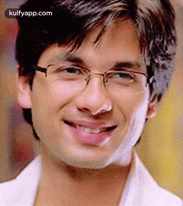 A Young Man Wearing Glasses Is Smiling For The Camera . GIF