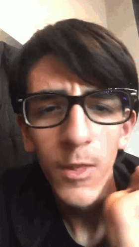 A Young Man Wearing Glasses Looks At The Camera GIF