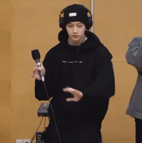 a young man wearing headphones and a beanie is holding a microphone and dancing .