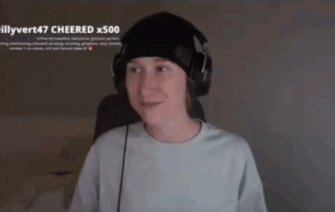 a young man wearing headphones and a beanie is sitting in front of a computer screen .