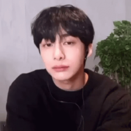 A Young Man Wearing Headphones And A Black Shirt Is Looking At The Camera . GIF
