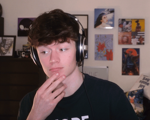 A Young Man Wearing Headphones And A Black Shirt That Says Mode GIF
