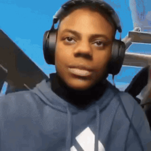 A Young Man Wearing Headphones And A Blue Hoodie Is Making A Funny Face . GIF