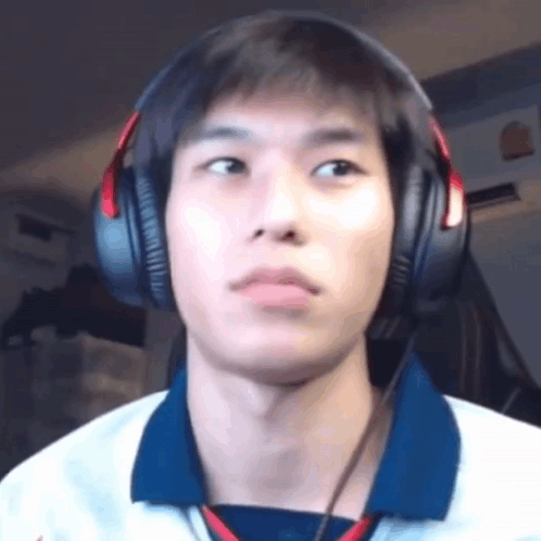 A Young Man Wearing Headphones And A Blue Shirt Is Looking At The Camera . GIF