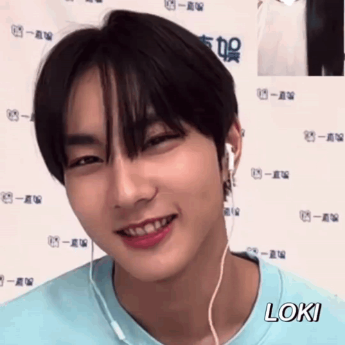 A Young Man Wearing Headphones And A Blue Shirt Is Smiling And Looking At The Camera . GIF