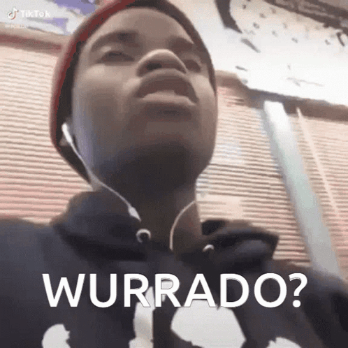 A Young Man Wearing Headphones And A Hat Is Making A Funny Face And Says Wurrado . GIF
