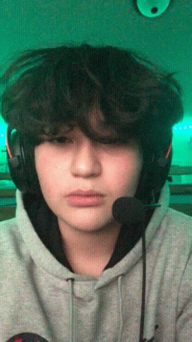A Young Man Wearing Headphones And A Microphone Looks At The Camera GIF
