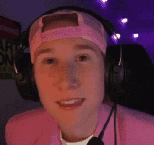 a young man wearing headphones and a pink hat is smiling .