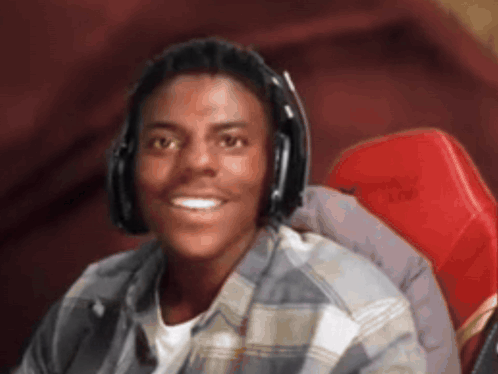 A Young Man Wearing Headphones And A Plaid Shirt Smiles For The Camera GIF