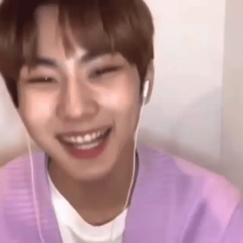 a young man wearing headphones and a purple shirt is smiling and looking at the camera .