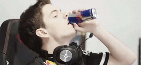 A Young Man Wearing Headphones Is Drinking A Red Bull Can GIF