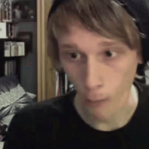 A Young Man Wearing Headphones Is Making A Funny Face While Looking At The Camera . GIF