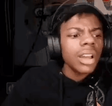 A Young Man Wearing Headphones Is Making A Funny Face While Sitting In Front Of A Microphone . GIF