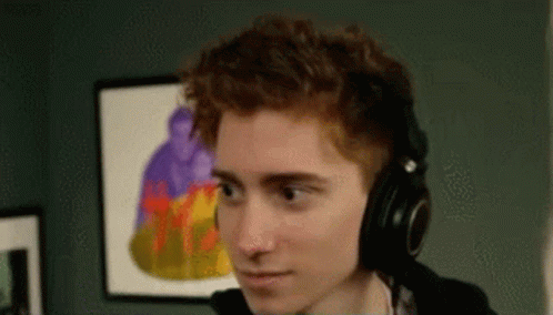 A Young Man Wearing Headphones Is Sitting In Front Of A Computer . GIF