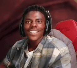 A Young Man Wearing Headphones Is Smiling And Sitting In A Red Chair . GIF