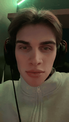 A Young Man Wearing Headphones Is Taking A Picture Of Himself GIF
