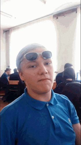 A Young Man Wearing Sunglasses And A Blue Shirt GIF