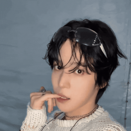 A Young Man Wearing Sunglasses And A White Sweater Looks At The Camera GIF