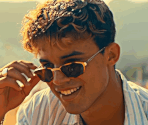 A Young Man Wearing Sunglasses Is Smiling For The Camera GIF