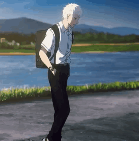 A Young Man With A Backpack Is Walking Down A Street . GIF