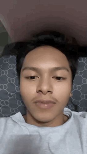 A Young Man With A Mustache Is Laying On A Bed And Making A Funny Face . GIF