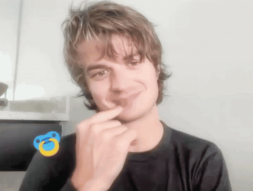 A Young Man With A Pacifier On His Finger Is Smiling GIF