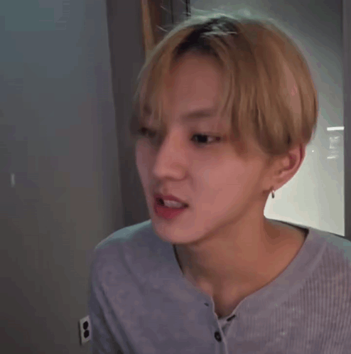 A Young Man With Blonde Hair Is Making A Funny Face While Wearing A Blue Shirt . GIF