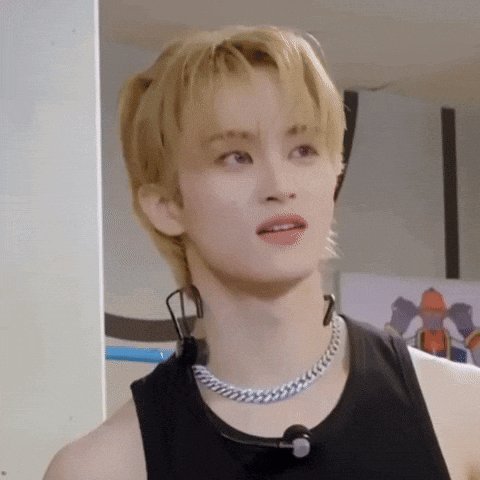 A Young Man With Blonde Hair Is Wearing A Black Tank Top And A Silver Chain Necklace . GIF