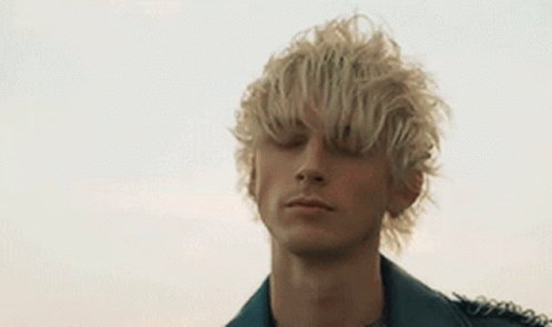 A Young Man With Blonde Hair Is Wearing A Leather Jacket And A Black Shirt . GIF