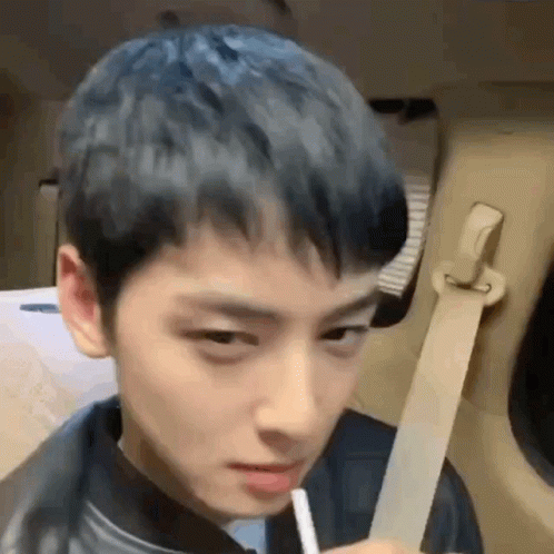 A Young Man With Blue Hair Is Sitting In The Back Seat Of A Car Holding A Straw . GIF