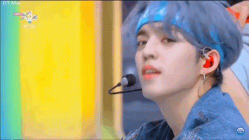A Young Man With Blue Hair Is Wearing A Headband And Earphones While Singing Into A Microphone . GIF