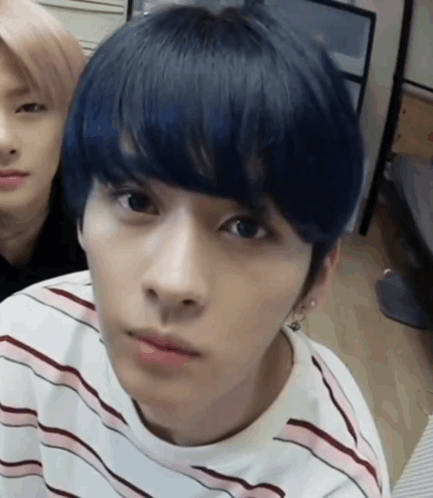 A Young Man With Blue Hair Is Wearing A Striped Shirt And Looking At The Camera . GIF