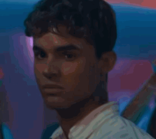 A Young Man With Curly Hair Is Holding A Glass Of Water GIF