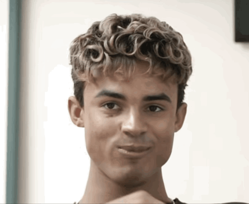 A Young Man With Curly Hair Is Making A Face GIF