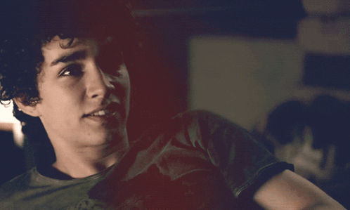 A Young Man With Curly Hair Is Wearing A Black T-Shirt GIF
