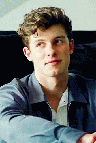 A Young Man With Curly Hair Is Wearing A Blue Jacket And A White Shirt GIF