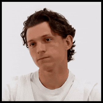 A Young Man With Curly Hair Is Wearing A White Shirt And Sweater . GIF