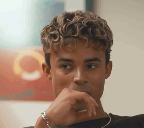 A Young Man With Curly Hair Looks At The Camera GIF