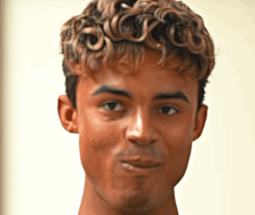 A Young Man With Curly Hair Looks At The Camera GIF