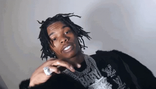 A Young Man With Dreadlocks And A Ring On His Finger Is Wearing A Black Jacket And A Necklace . GIF