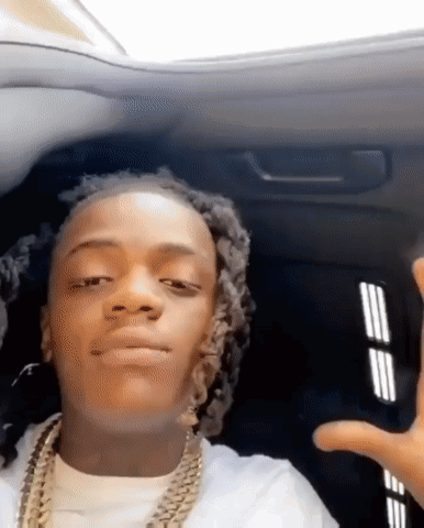 A Young Man With Dreadlocks Is Sitting In The Back Seat Of A Car And Making A Funny Face . GIF