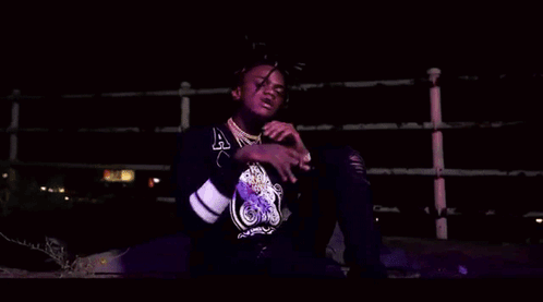A Young Man With Dreadlocks Is Smoking A Cigarette In A Dark Room . GIF
